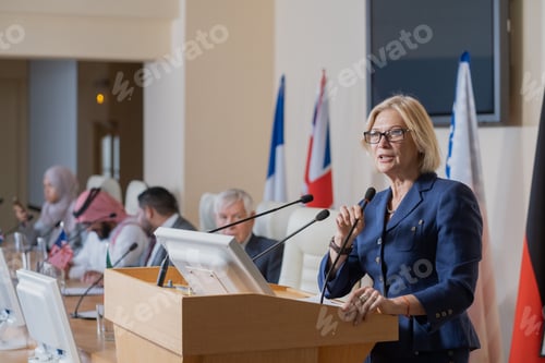 Preview: Mature female speaker in elegant suit making report