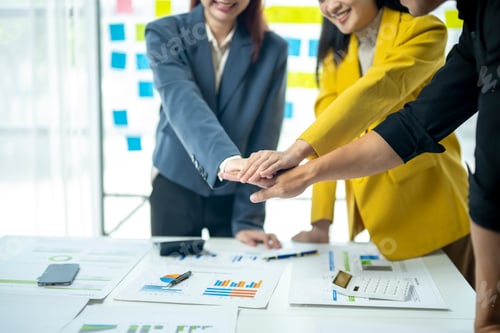 Preview: Three people are standing around a table, one of them is wearing a yellow jacket.