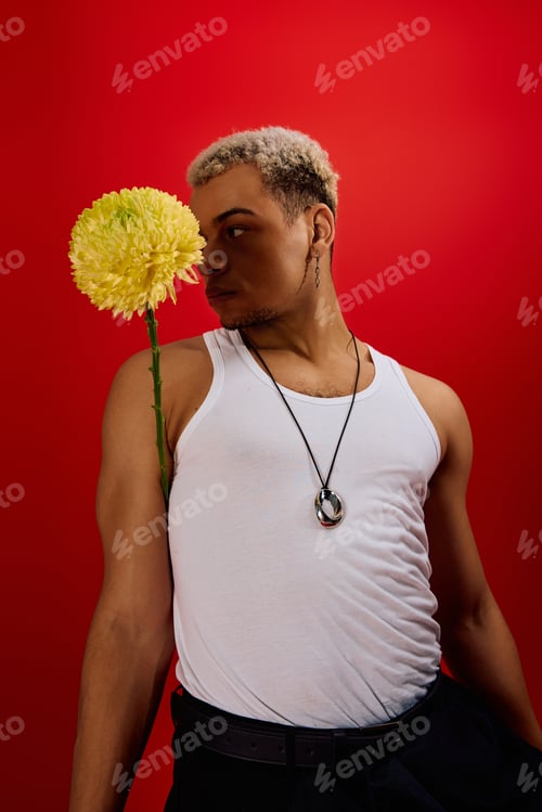 Preview: Young man with dyed hair poses confidently in a vibrant red studio setting