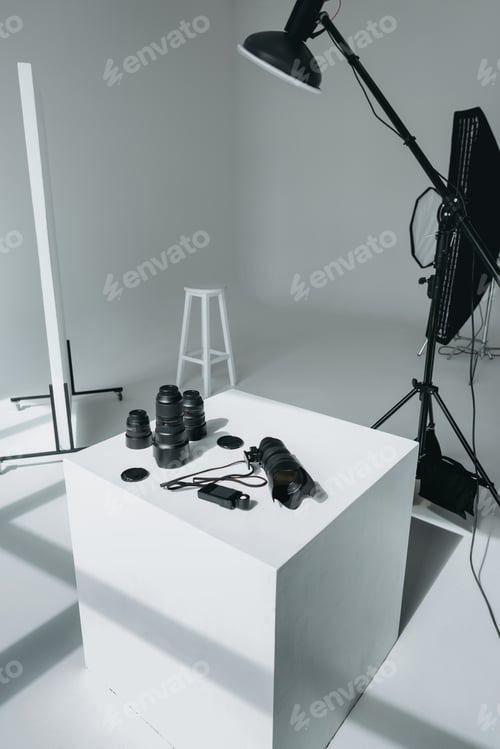 Preview: digital photo camera, lenses and light meter in photo studio with lighting equipment