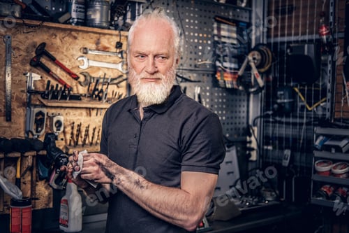 Preview: Old craftsman wiping his hands around bench in workshop