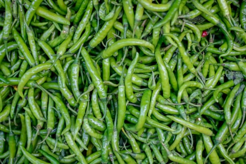 Preview: Top view of green spicy peppers in the market