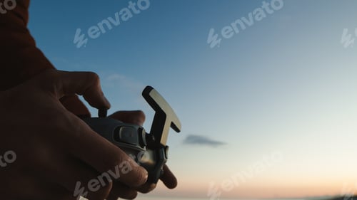 Preview: Silhouette of hand pilot of an fpv drone at sunset