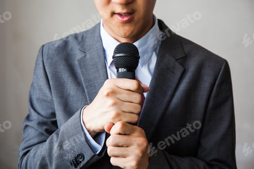 Preview: Man in business suit holding a microphone