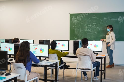 Preview: Multiracial students using computers during business class wearing safety masks at school