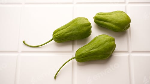 Preview: A pile of green chayote squash on white table