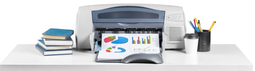 Preview: Printer in an office printing reports with books and stationery on the desk
