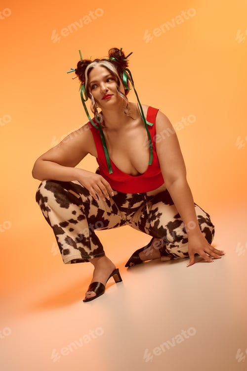 Preview: Young woman showcases unique style with ribbons and bold fashion against orange backdrop