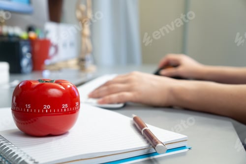Preview: Selective focus shot of a kitchen timer in the form of a tomato on a notebook