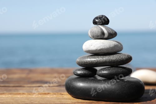 Preview: Stack of stones on wooden pier near sea seascape, space for text. Zen concept
