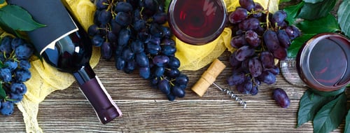 Preview: Wineglasses with red wine, bottle, corkscrew, blue grapes, leaves on a wooden table