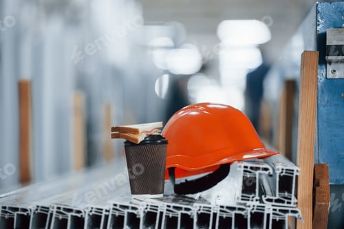 Preview: Orange hard hat on objects in the factory. No people. Conception of lunch break