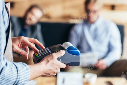 Preview: cropped shot of waiter using payment terminal in cafe