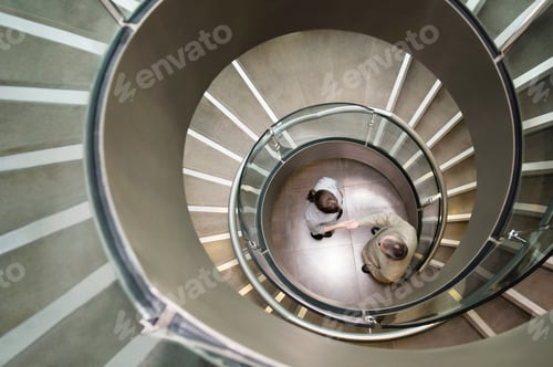 Preview: Business duo shake hands in a stairwell
