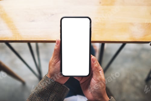 Preview: a woman holding mobile phone with blank white screen while sitting in office