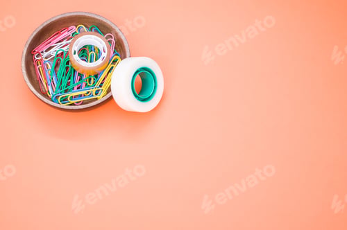 Preview: Top view of colorful paper clips and adhesive tapes in a wooden bowl
