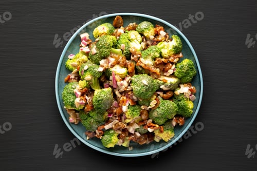 Preview: Homemade Broccoli Bacon Salad on a Plate on a black background, top view. Flat lay, overhead.