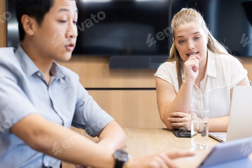 Preview: Discussing business strategy, multiracial colleagues using laptop and tablet in office meeting