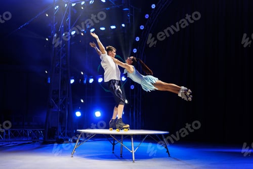 Preview: Young pair of acrobats, man and woman, on roller skates perform in a circus on a small round stage.