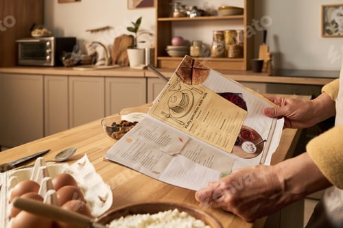 Preview: Middle Aged Woman Reading Recipe Book While Preparing Ingredients