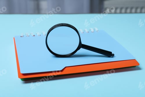 Preview: Magnifying glass and notepad on blue background