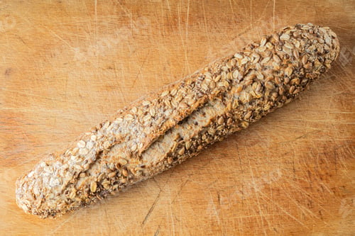 Preview: Rustic multigrain baguette with oat seeds on wooden cutting board.