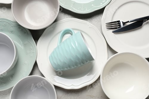 Preview: Beautiful ceramic dishware, cup and cutlery on light grey table, flat lay