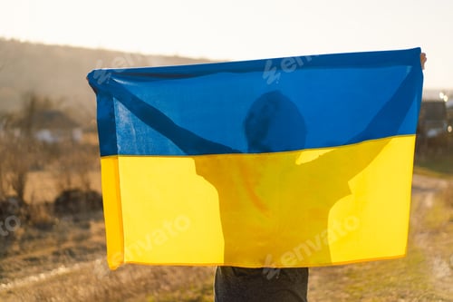 Preview: Woman holding a yellow and blue flag of Ukraine in outdoors
