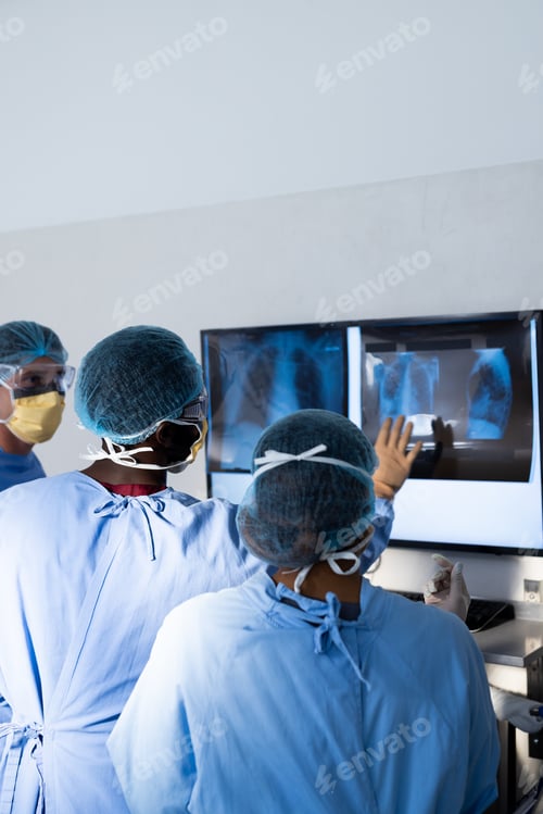 Preview: Diverse group of surgeons discussing x rays on screen in operating theatre, copy space
