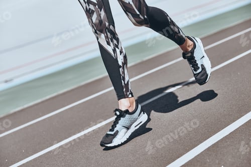 Preview: Determined to win. Close up of young woman in sports shoes jogging while exercising outdoors