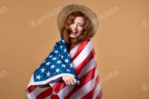 Preview: Smiling woman with national USA flag on beige background. American patriot, 4th of July