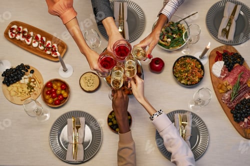 Preview: Above view of hands of several intercultural people clinking with drinks