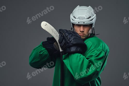 Preview: Hockey player wearing black protective uniform holds a hockey stick on a gray background.