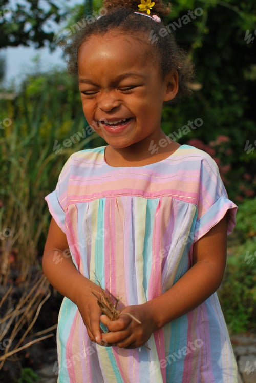 Preview: Little girl of mixed race wearing a Rainbow dress and laughing