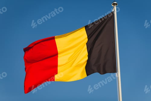 Preview: National flag of Belgium on flagpole in front of blue sky. Black, yellow and red colours