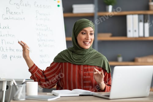 Preview: Muslim English teacher pointing on board, explaining lesson to students