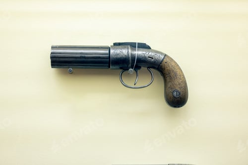 Preview: Old vintage pepper-box revolver isolated on a light yellow background