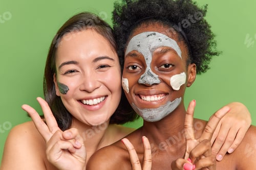 Preview: Pleased multiethnic young women stand closely to each other have fun undergo beauty procedures apply