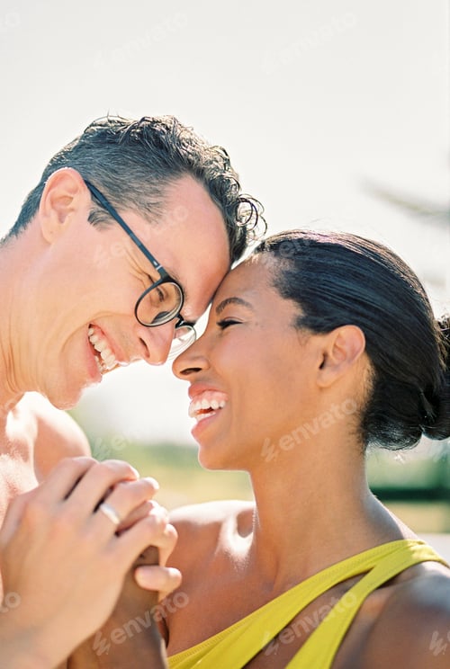 Preview: Smiling husband holds hands of laughing wife touching her foreheads