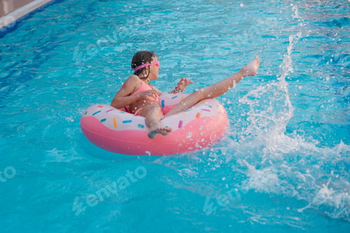 Preview: young girl with inflatable donut in swimming pool