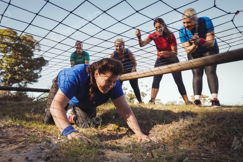 Preview: Woman being cheered bye her teammates during obstacle course training