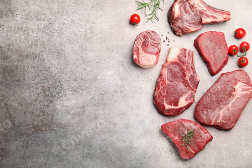 Preview: Pieces of raw beef meat, spices and tomatoes on grey table, flat lay. Space for text