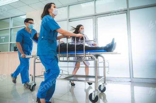 Preview: Medical assistant and nurse carrying sick elderly woman lying on medical gurney at hospital