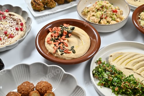 Preview: plates filled with various foods on a table that includes hummus, celery