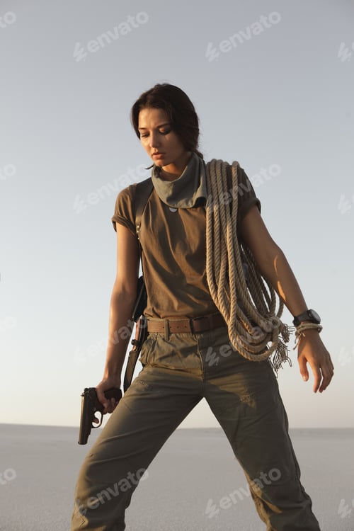 Preview: Woman Standing With a Gun Outdoors in Desert