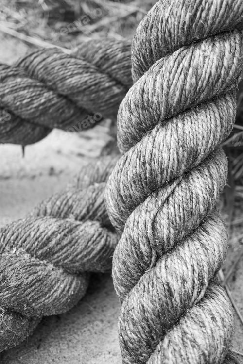 Preview: Vertical black and white shot of a thick rope in a blurred background