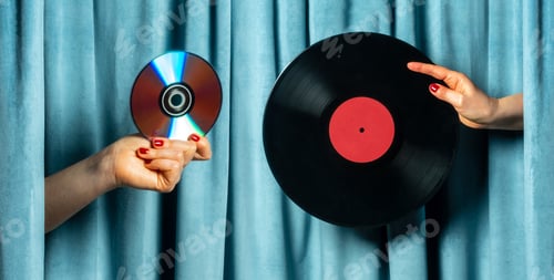 Preview: Female hand holding vinyl record and cd disc against blue velvet curtain