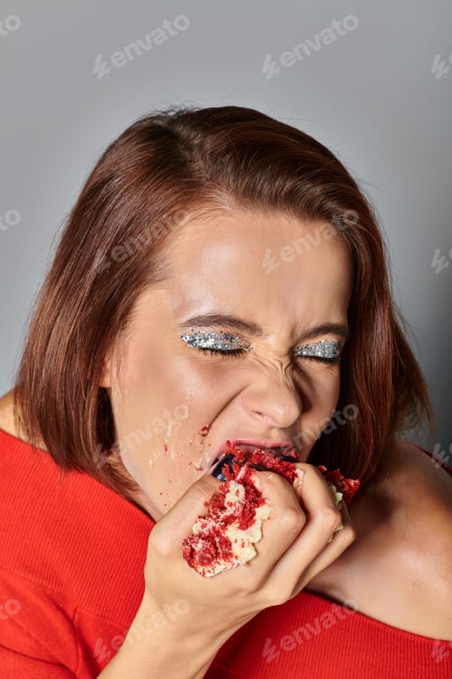 Preview: hungry birthday girl with closed eyes biting delicious piece of red velvet cake on grey background