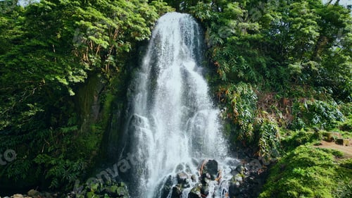 Preview: Tropical waterfall flowing down on sunny day. Mountain water stream falling