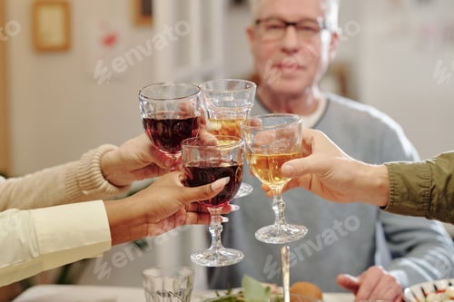 Preview: Hands of members of intercultural family clinking with glasses of wine